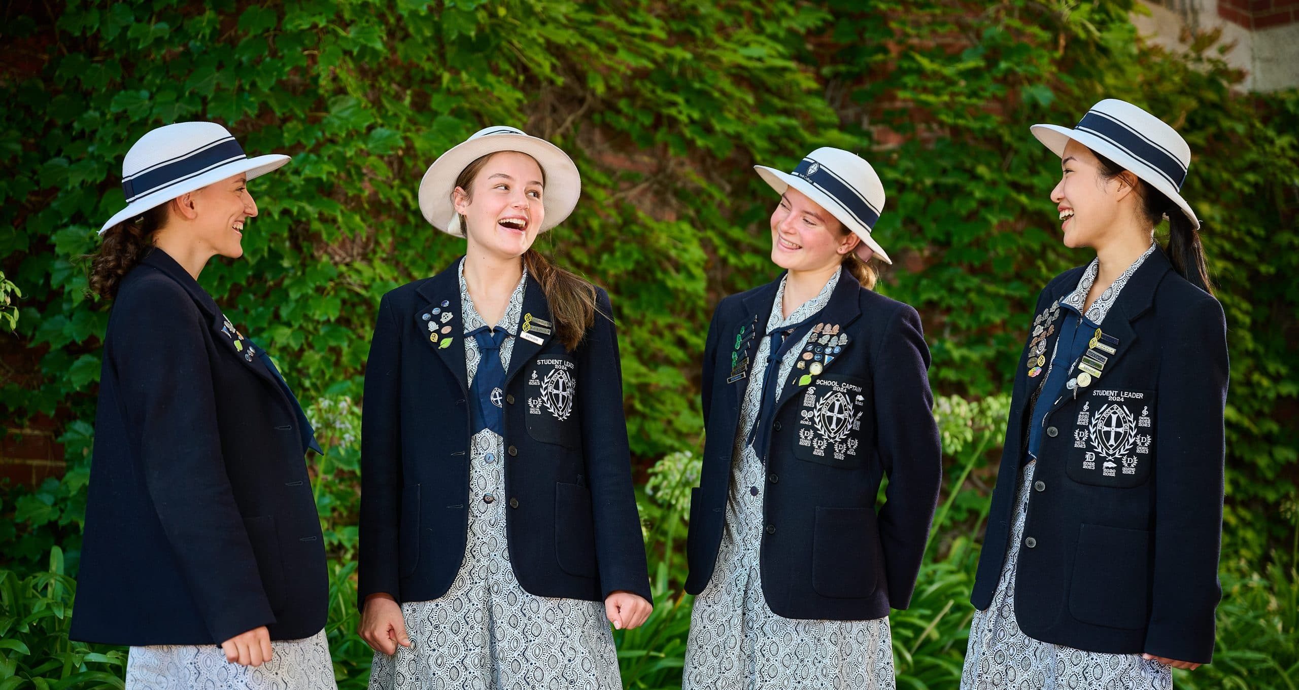 Four students in uniform smiling outdoors