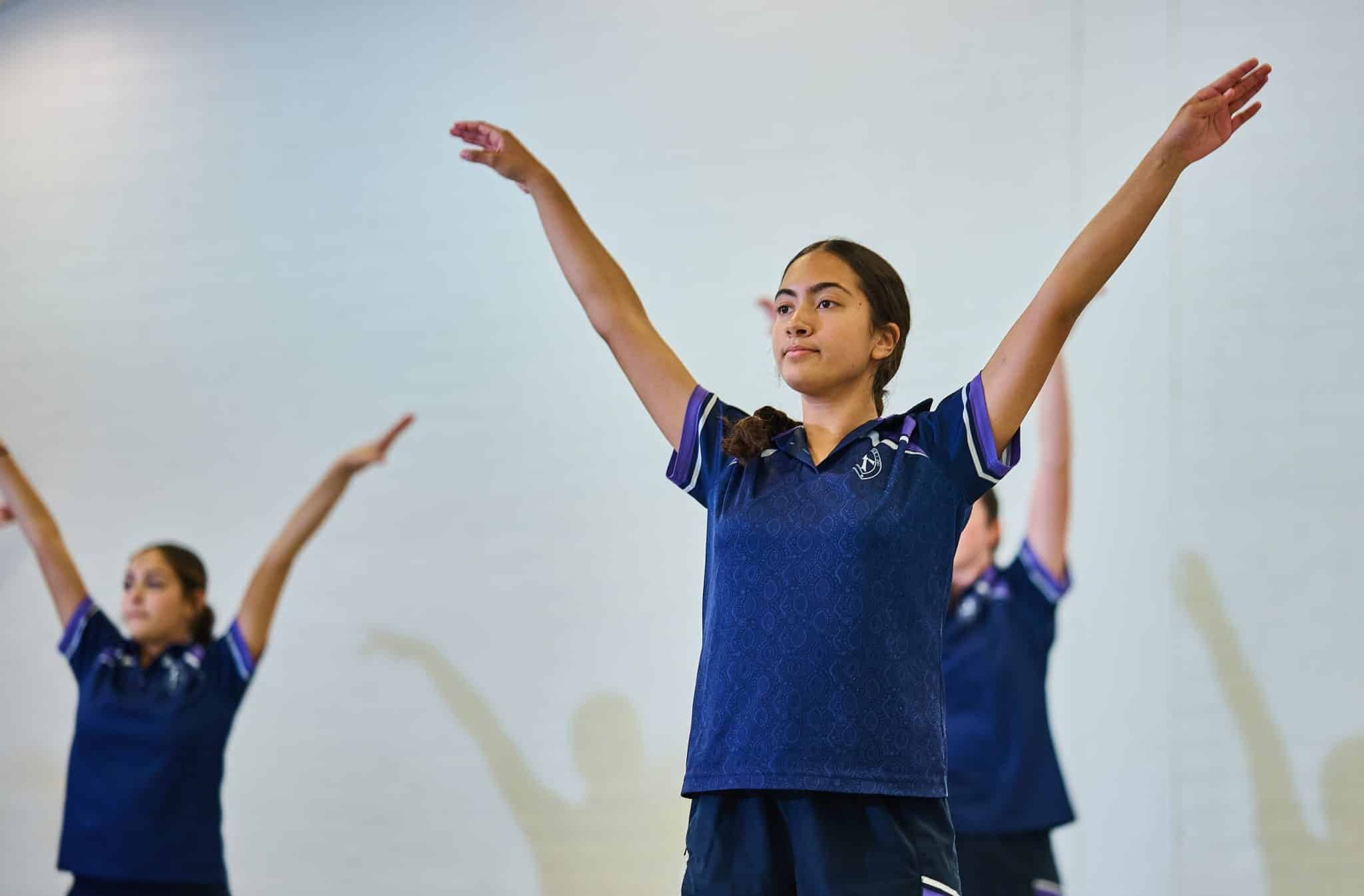 Students doing physical exercise in school uniforms.