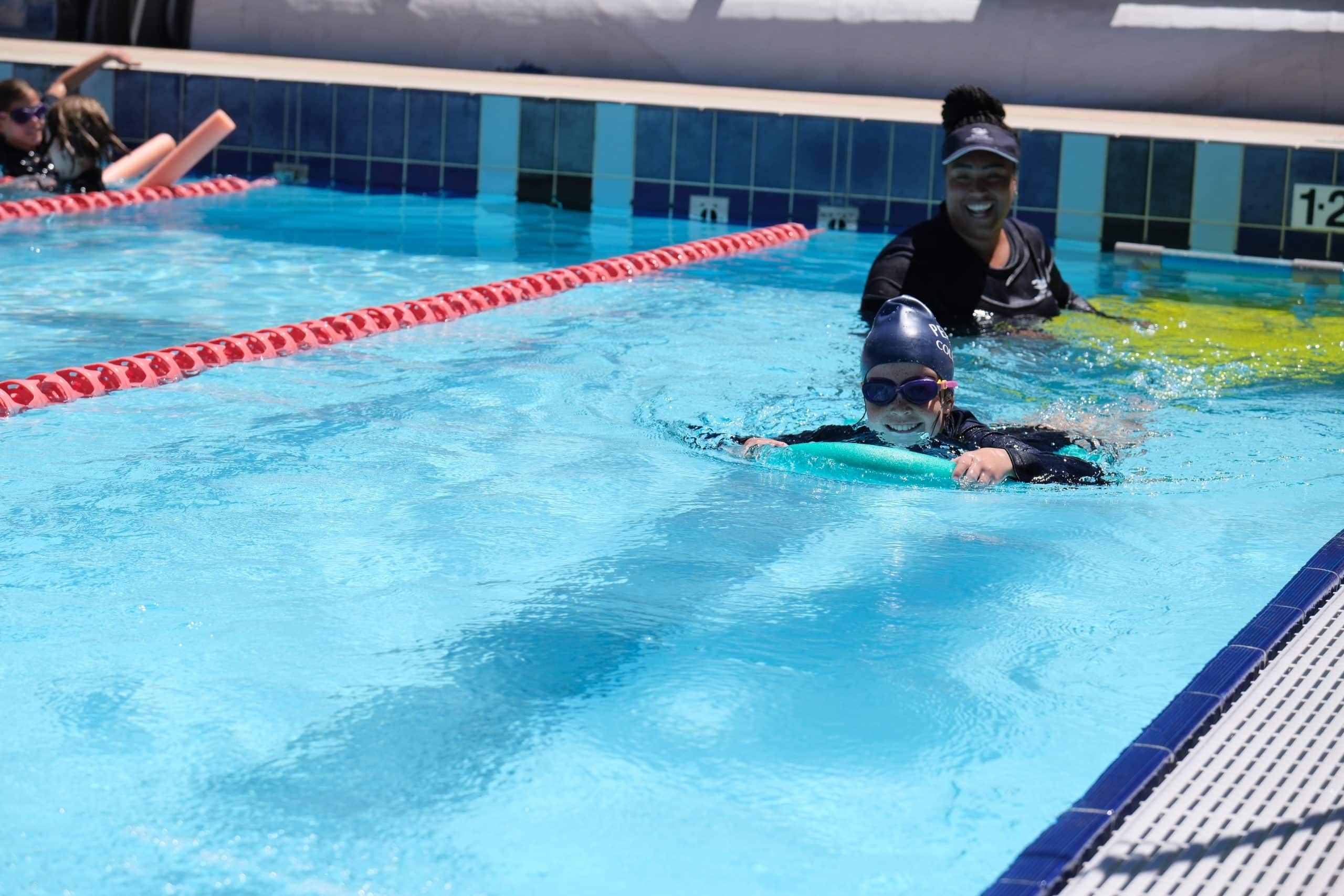 Child learning to swim with instructor.