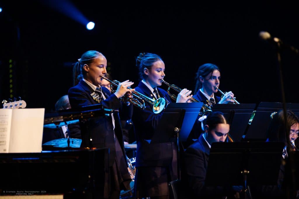 School band students playing trumpets on stage.